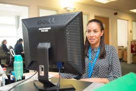 An NHS admin worker typing at a computer